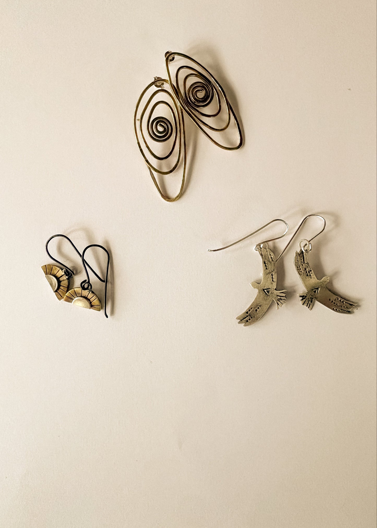 Set of three pairs of earrings on a beige background