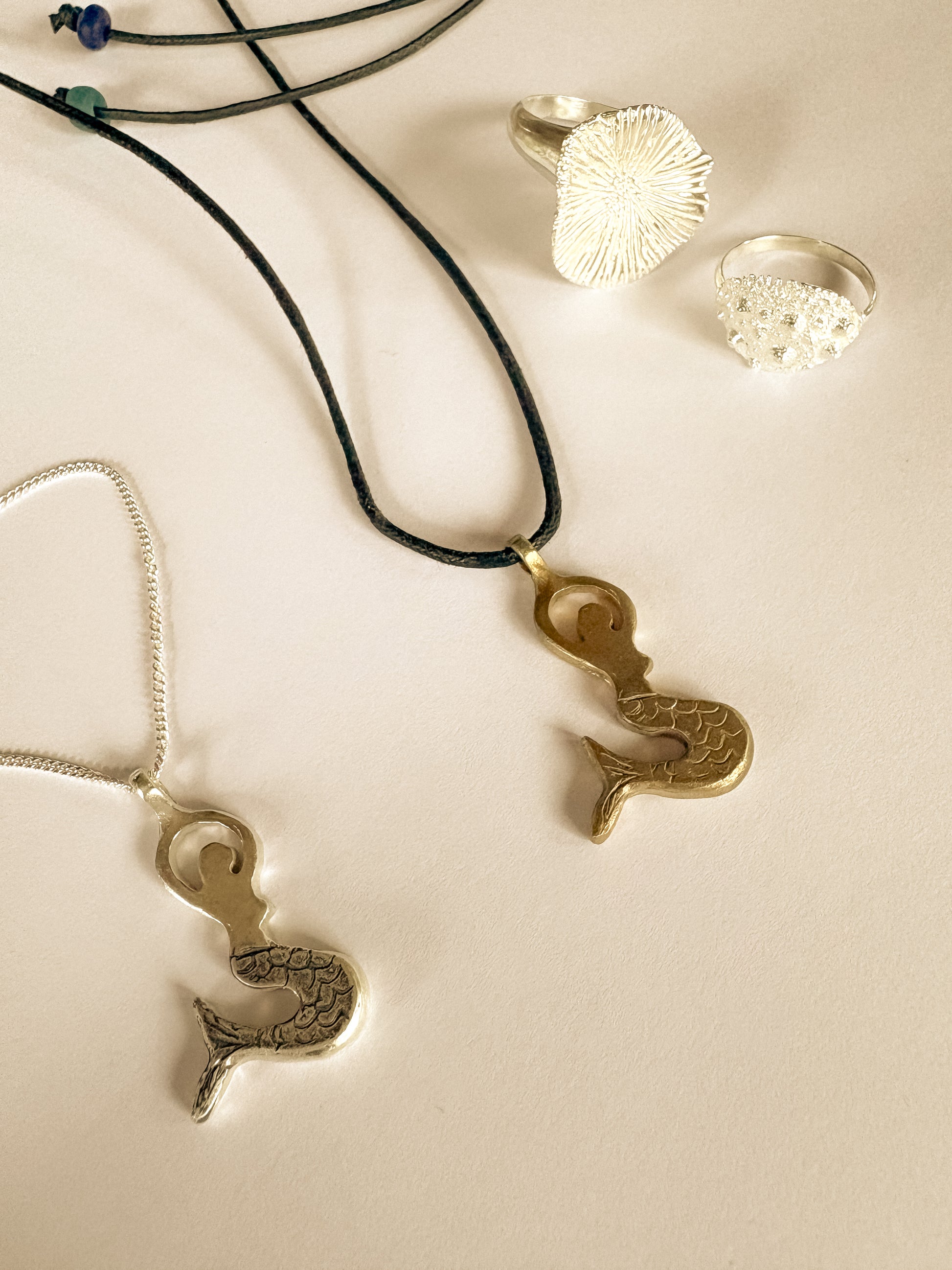 Mermaid pendant necklaces on a light background