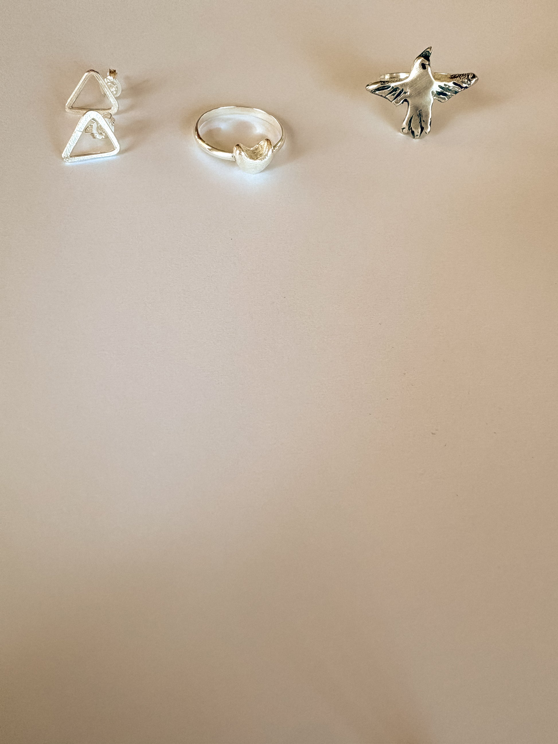 Three silver rings on a beige background