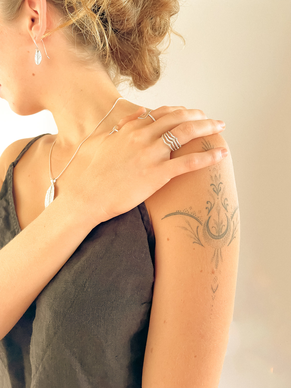 A close-up lifestyle shot of a woman, showcasing a silver twig cast ring.  